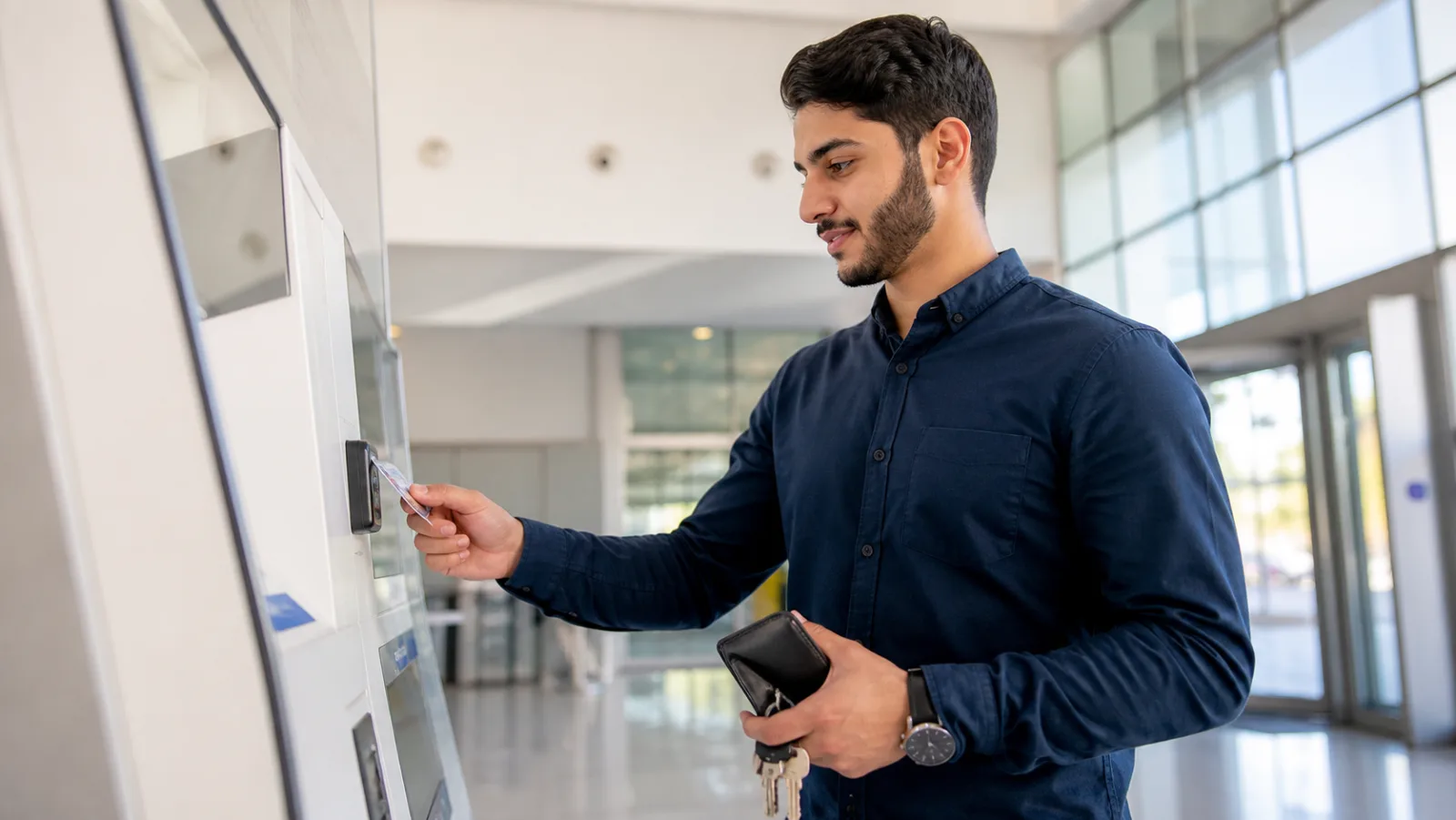 Young adult paying a household bill at a self-service kiosk